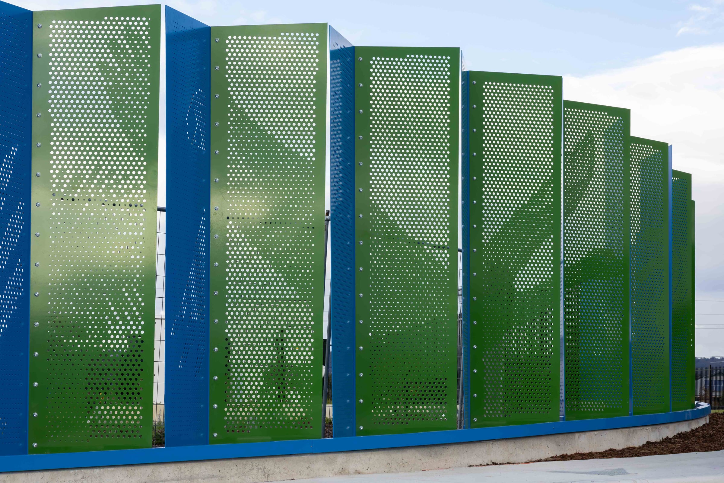 Late light warms the green side of the pleated screen at Hazelmere, blue edges folding away.