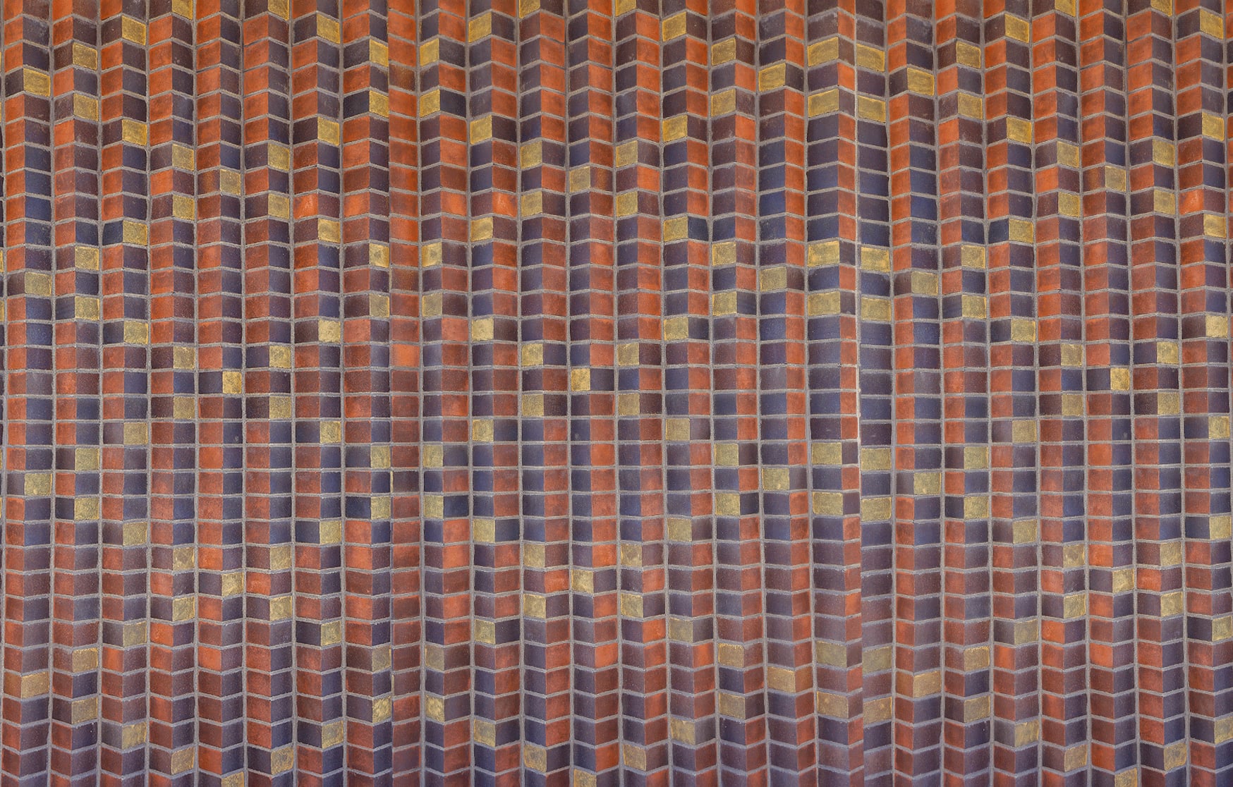 Straight on view of the Queenslea chevron brickwork, its red, blue and gold stained bricks reading like woven cloth
