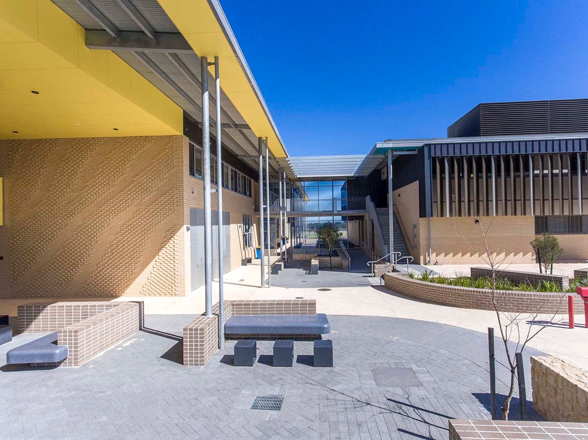 Brick tiled benches sit below the yellow canopy where the Rhythm and Flow wall turns into the Yanchep courtyard.