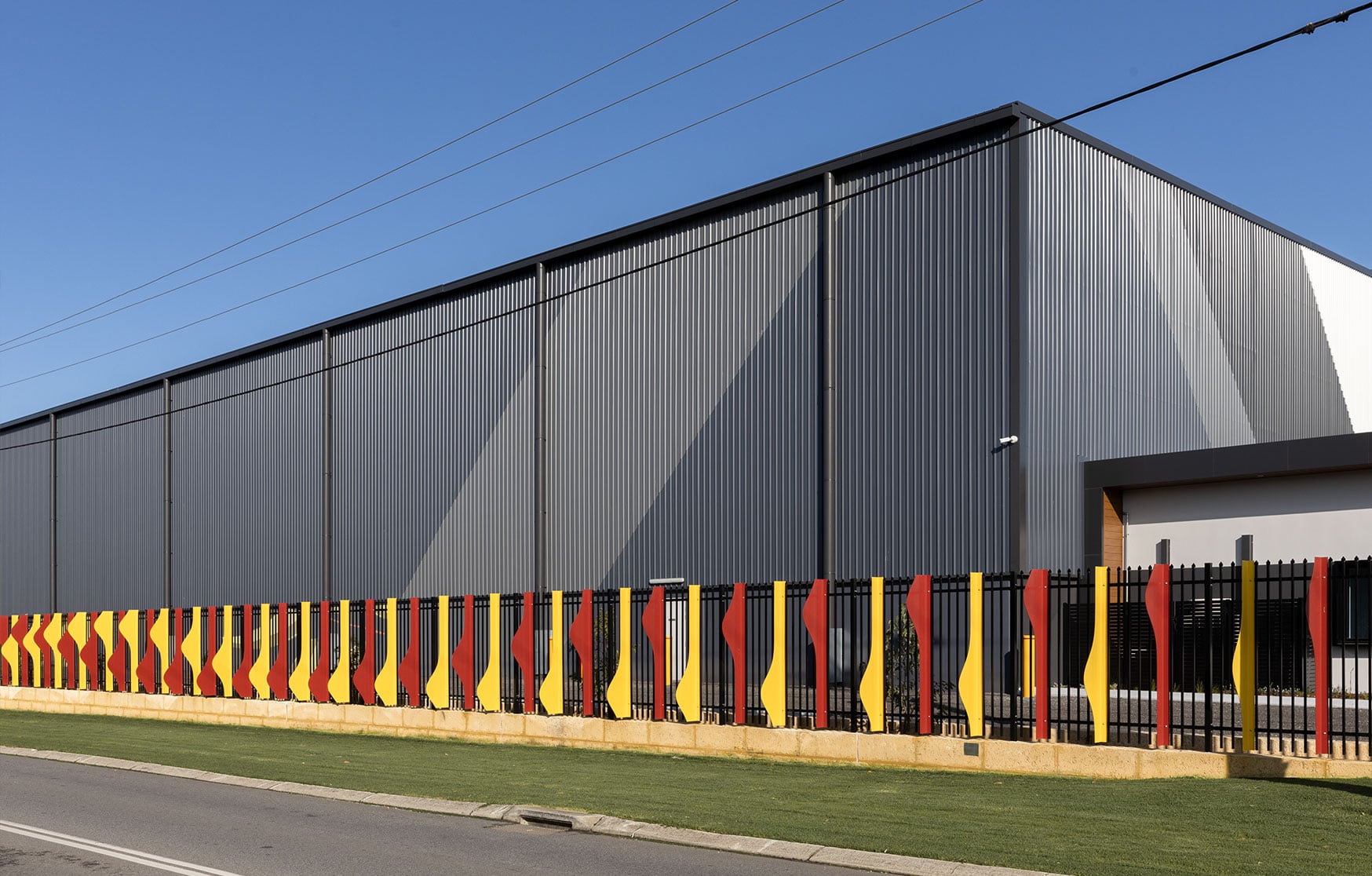 Long view along the Rippling Red Tails fence artwork marking the gateway to the Hazelmere industrial precinct