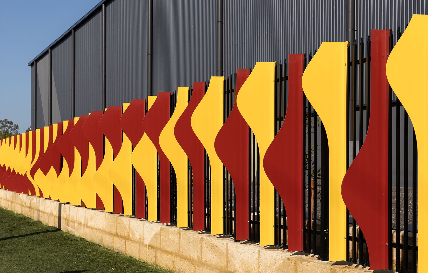 Twisting crimson and gold powdercoated aluminium fins catch the light in the Rippling Red Tails stage at Hazelmere.