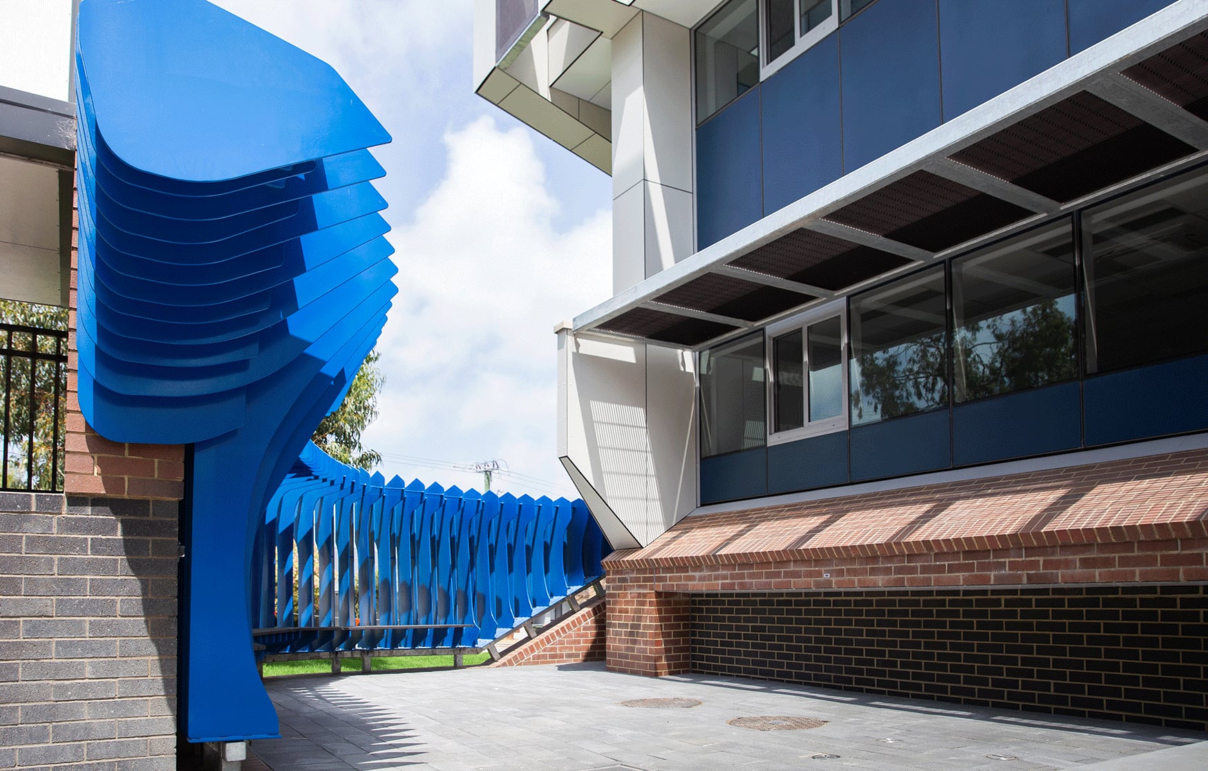 Blue painted steel fins of The Exchange wrap a brick corner beside new classroom buildings at Carine SHS.